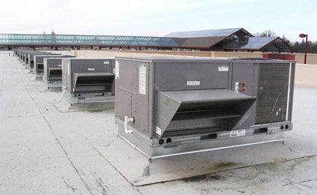 A row of air conditioners are sitting on top of a roof.