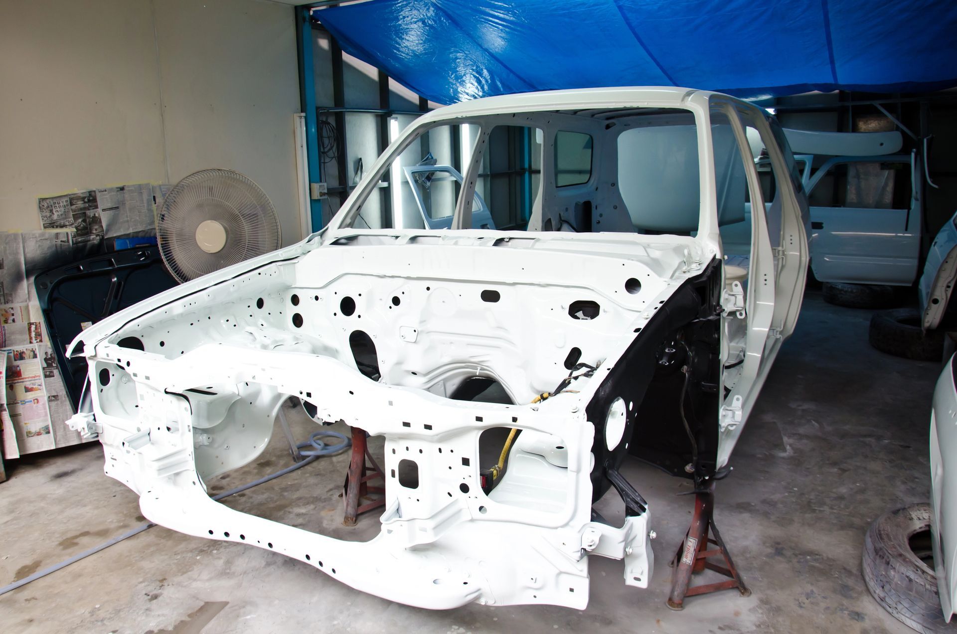 Telaio di un'auto bianca all'interno di un'officina, in fase di restauro.