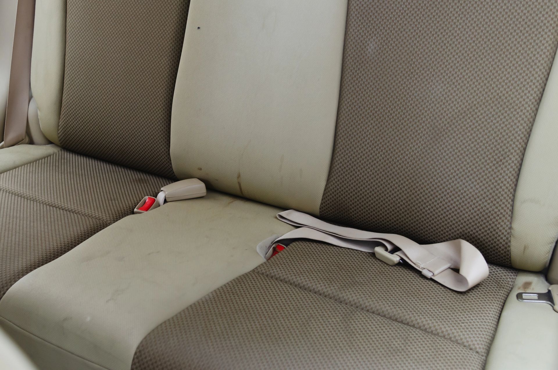 Sedile posteriore dell'auto beige e marrone con cinture di sicurezza.