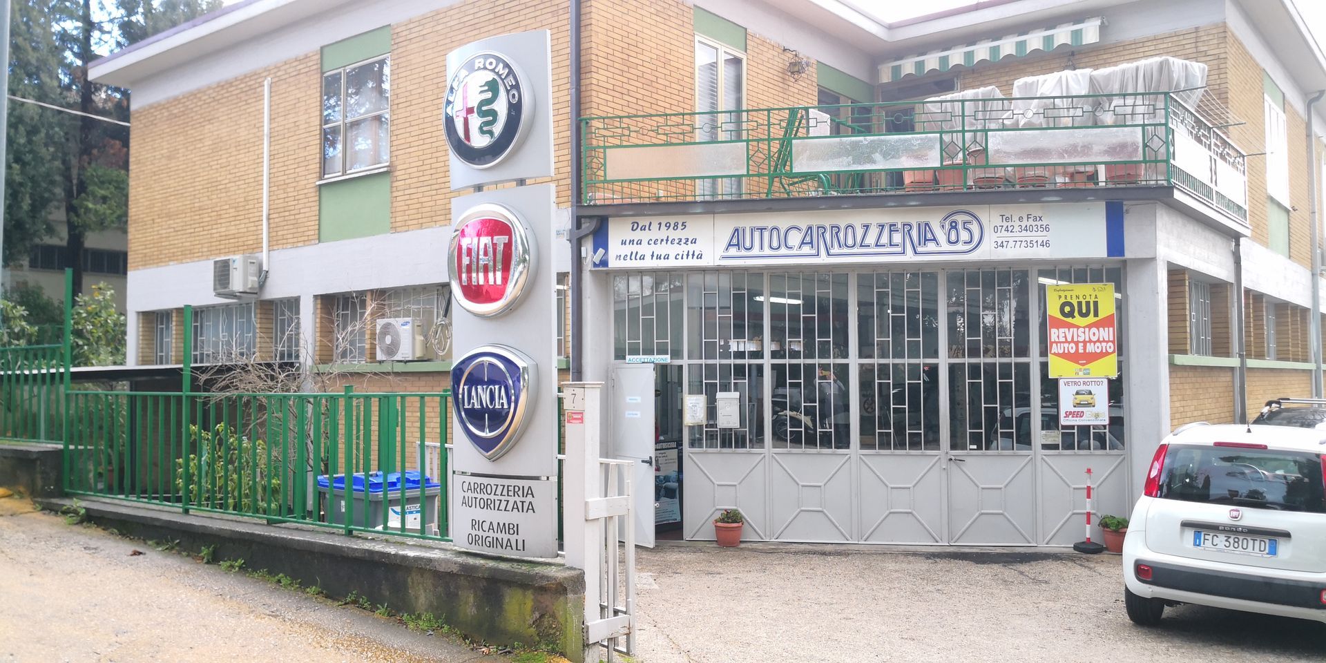 Esterno di un'officina con i loghi Alfa Romeo, Fiat e Lancia
