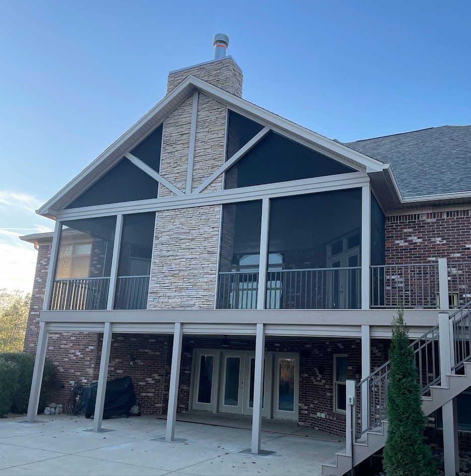 Brick house with a screened-in porch and chimney. Beige trim, dark screens, and a multi-level deck.