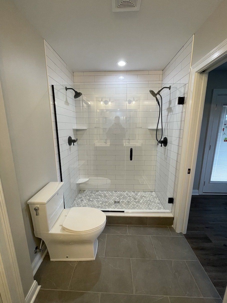 Modern bathroom with a glass shower and a white toilet. Gray tile flooring. White subway tile in the shower.