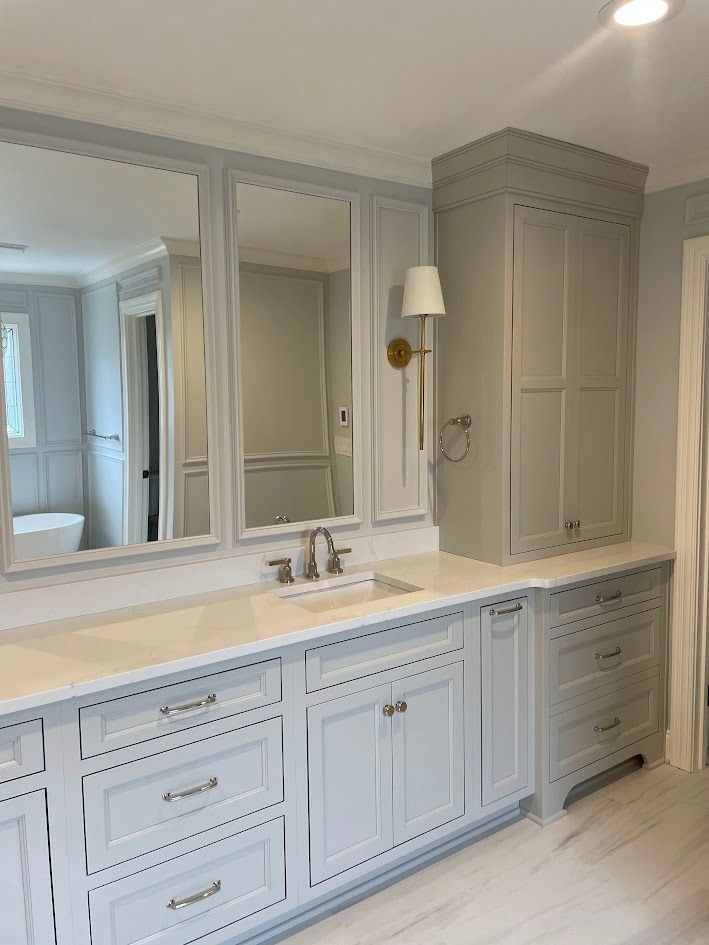 Light blue bathroom vanity with white countertop, mirrors, and storage cabinet.