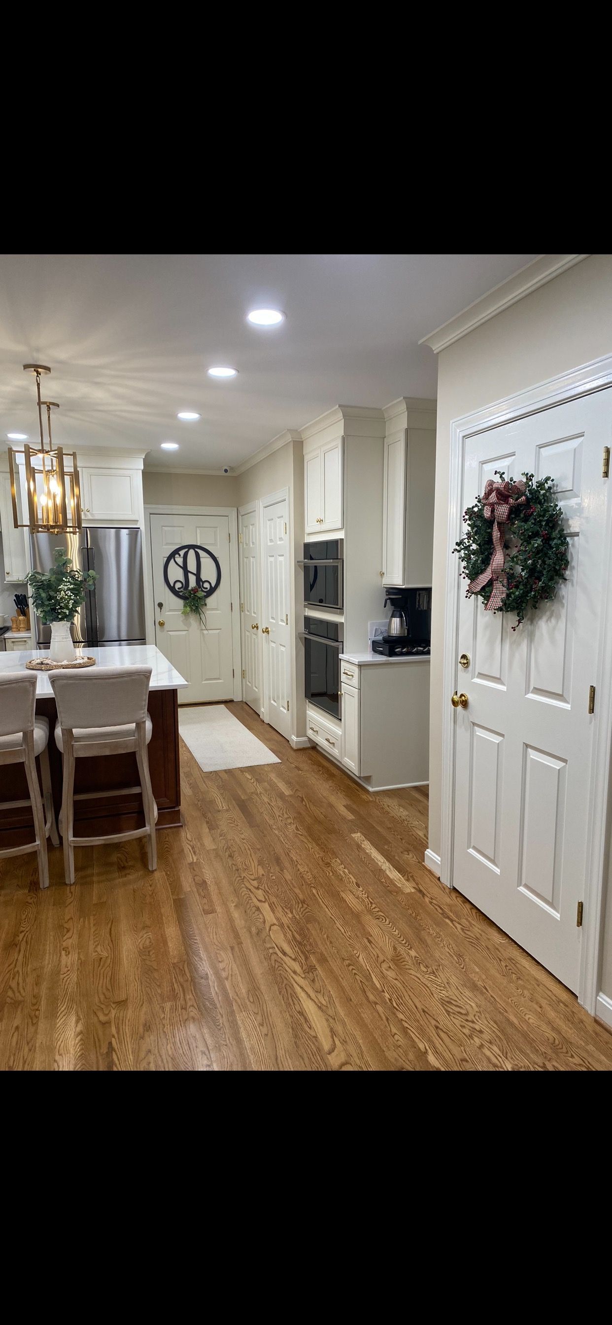 Kitchen with wooden floors, white cabinets, and a decorative wreath on a door.