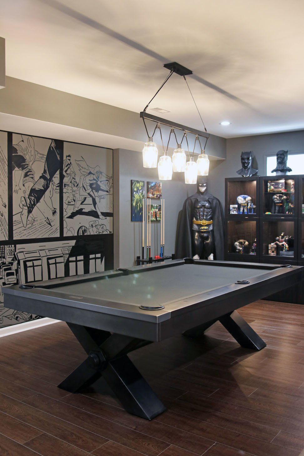 Pool table in a themed room with Batman decor.