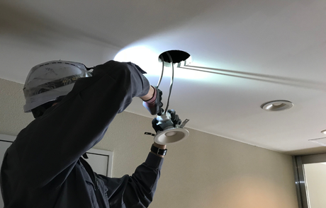 Persona instalando una luminaria empotrada en el techo. Los cables cuelgan.