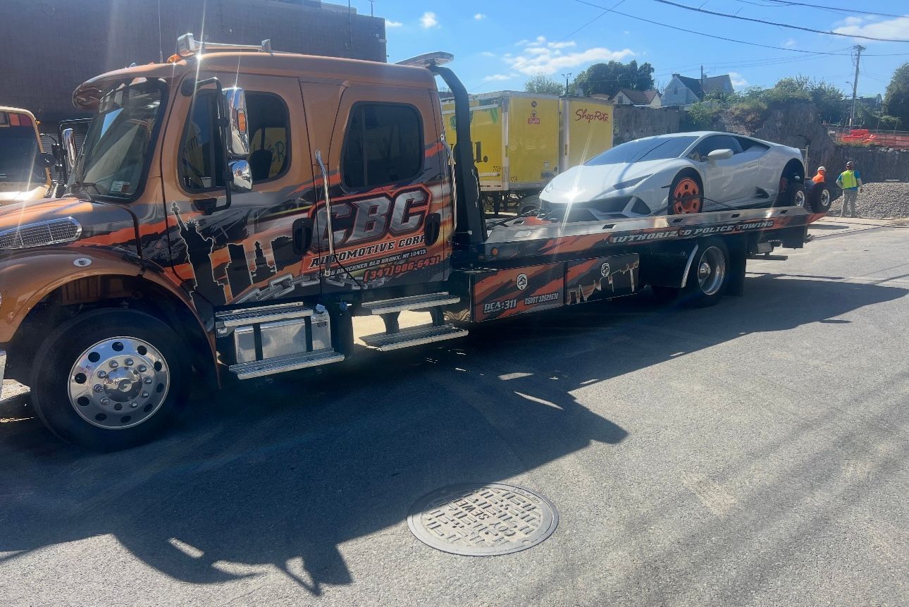 A tow truck is towing a car down a street.