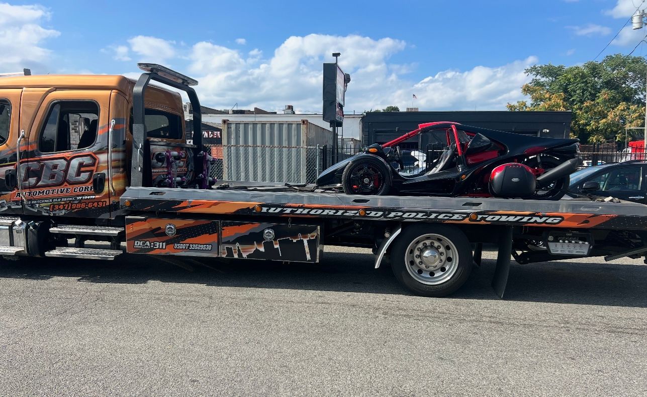 A tow truck with two motorcycles on the back is parked in a parking lot.