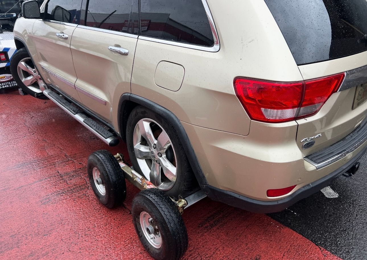 A jeep is being towed by a trailer with wheels attached to it