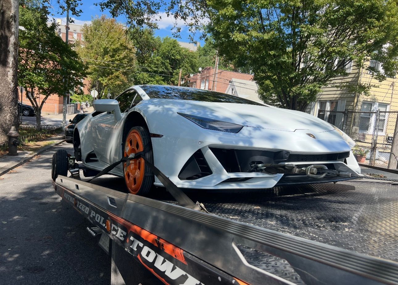 A white lamborghini is sitting on top of a tow truck.