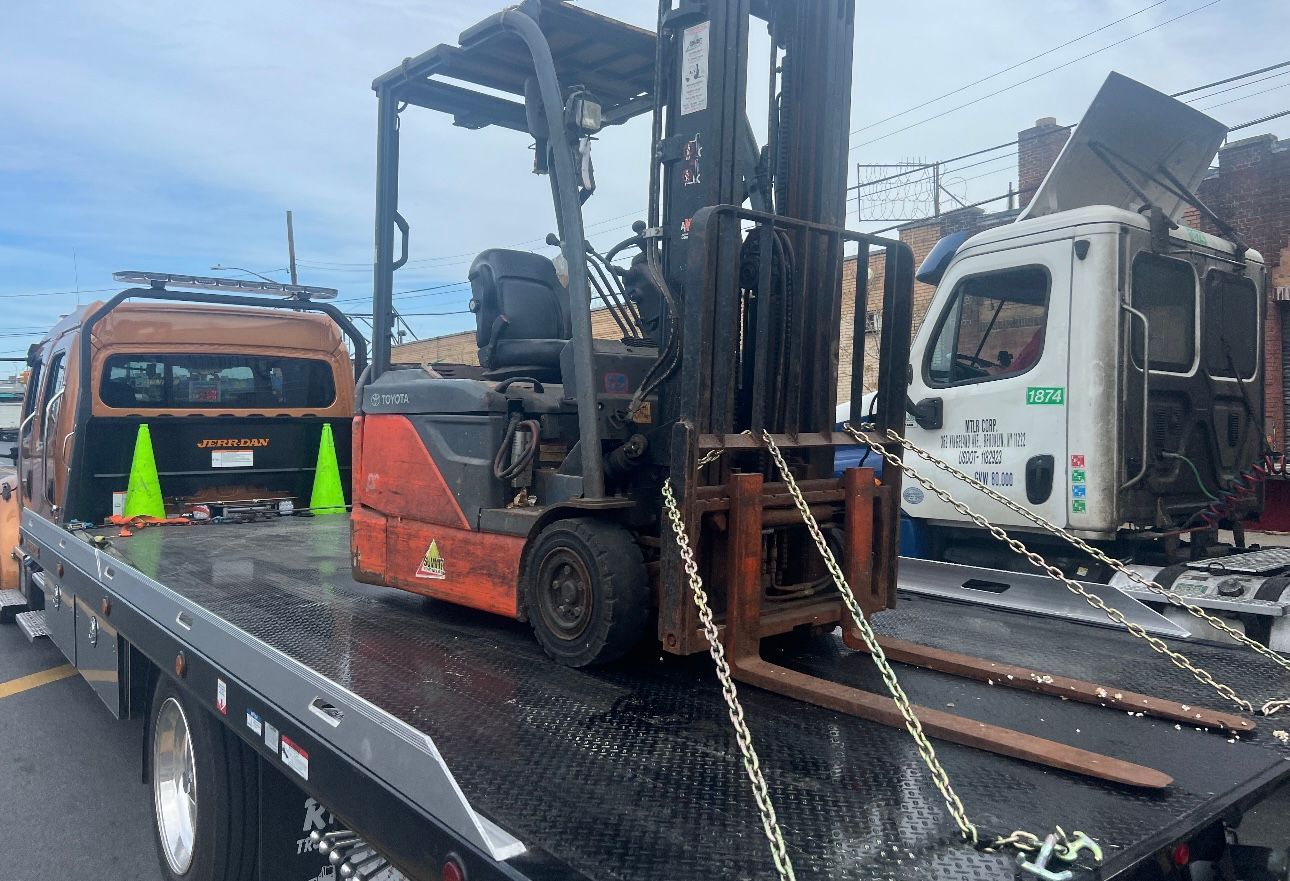 A forklift is sitting on top of a tow truck.