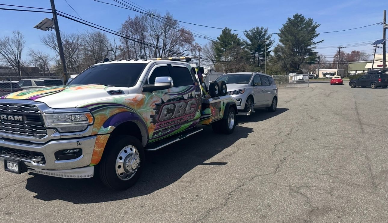 A tow truck is towing a white van down a road.