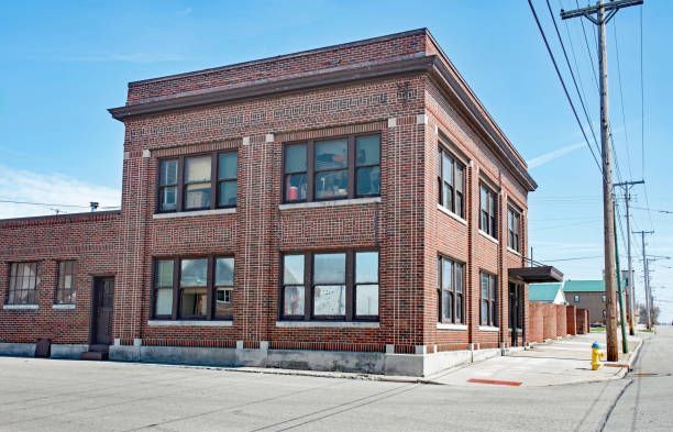 A large brick building with a lot of windows is on the corner of a street.
