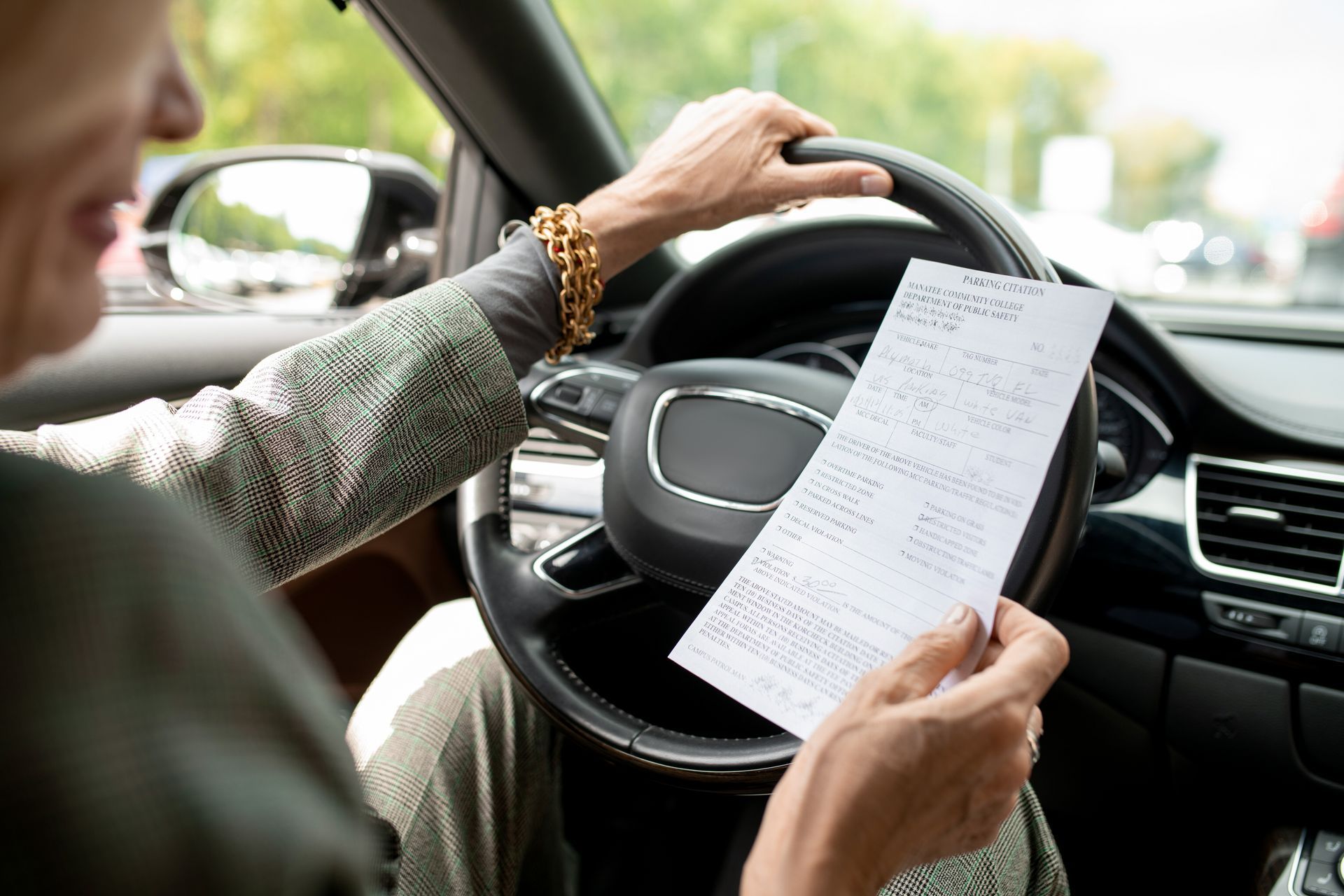 Person in a car looking at a receipt while holding the steering wheel.