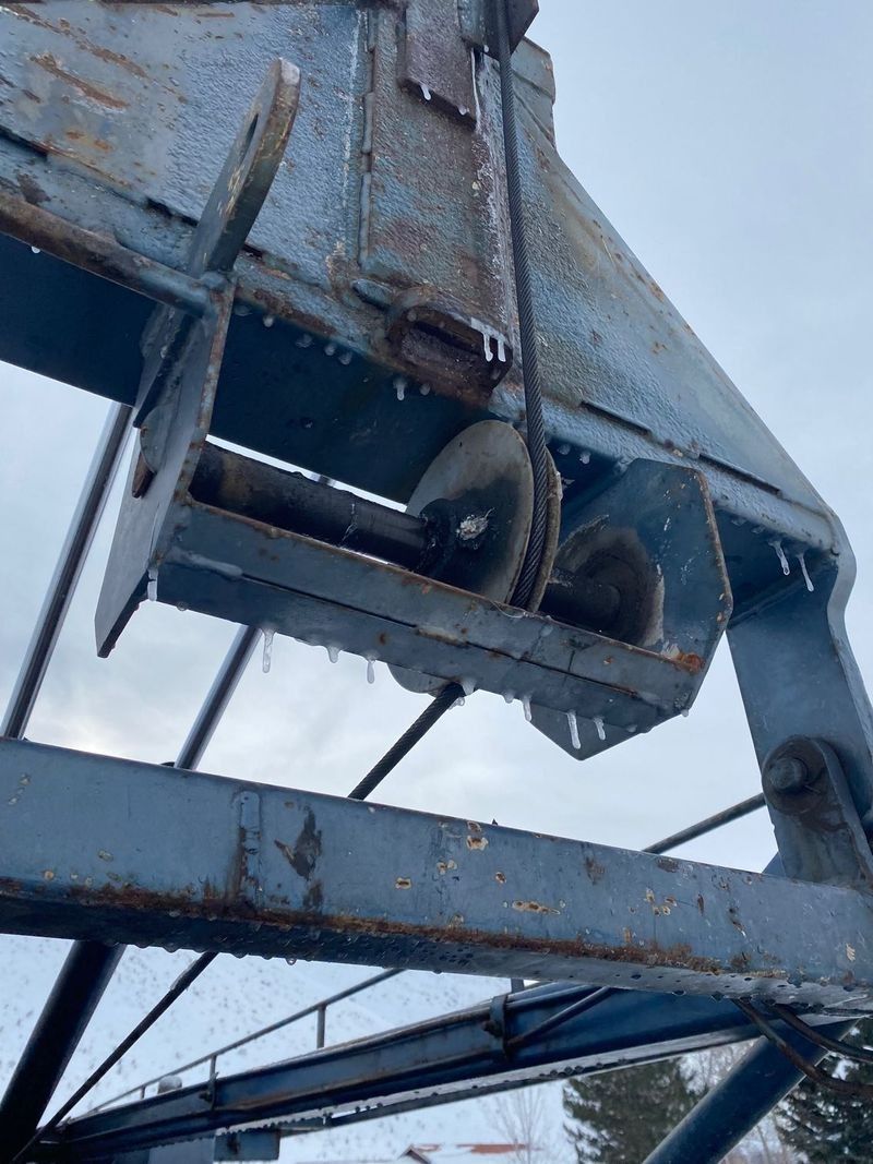 Rusty metal tower with loudspeakers or sirens mounted underneath against a cloudy sky