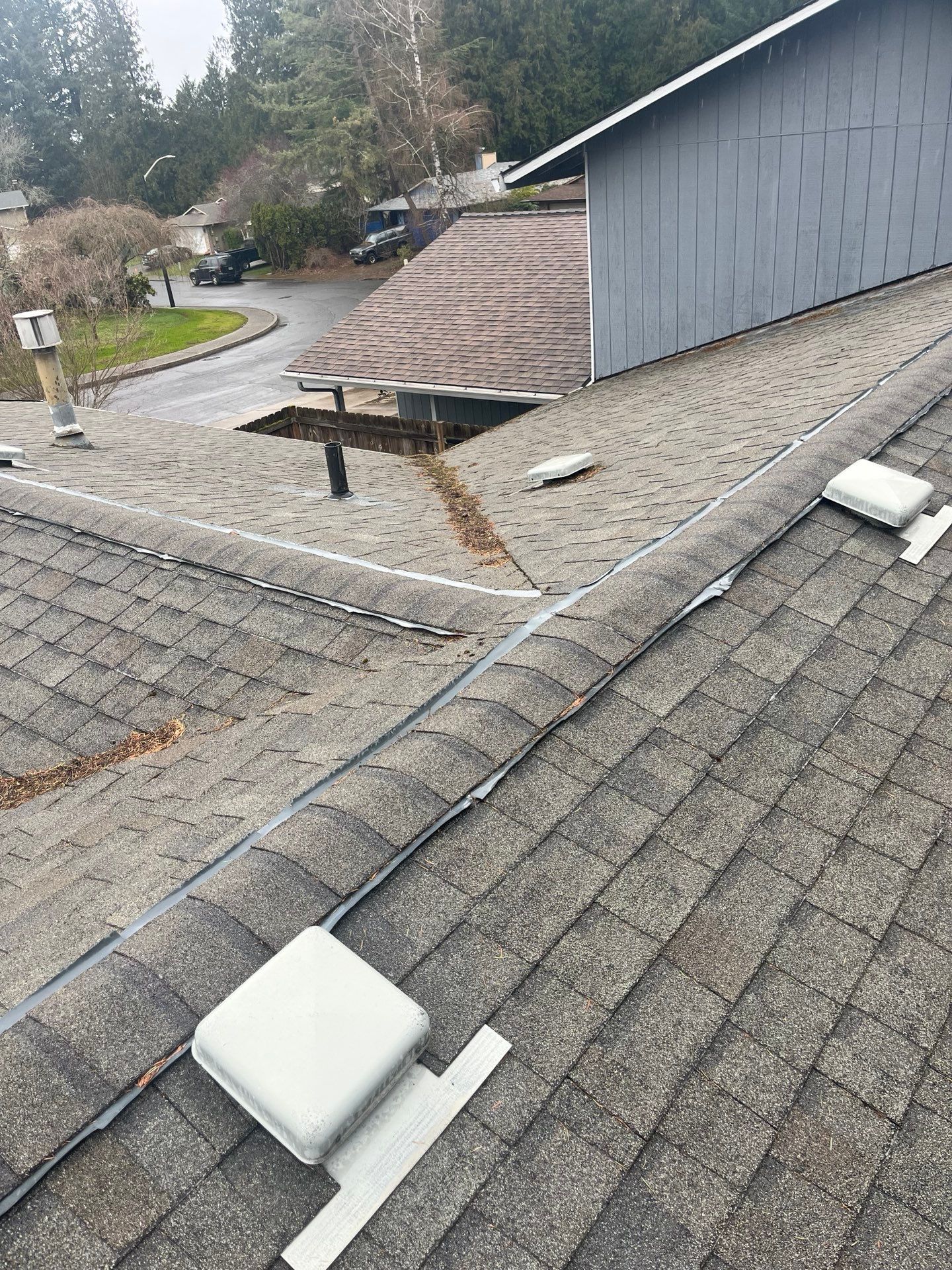 Rooftop with gray shingles and white fixtures; a large hole and rust-colored stains are visible.