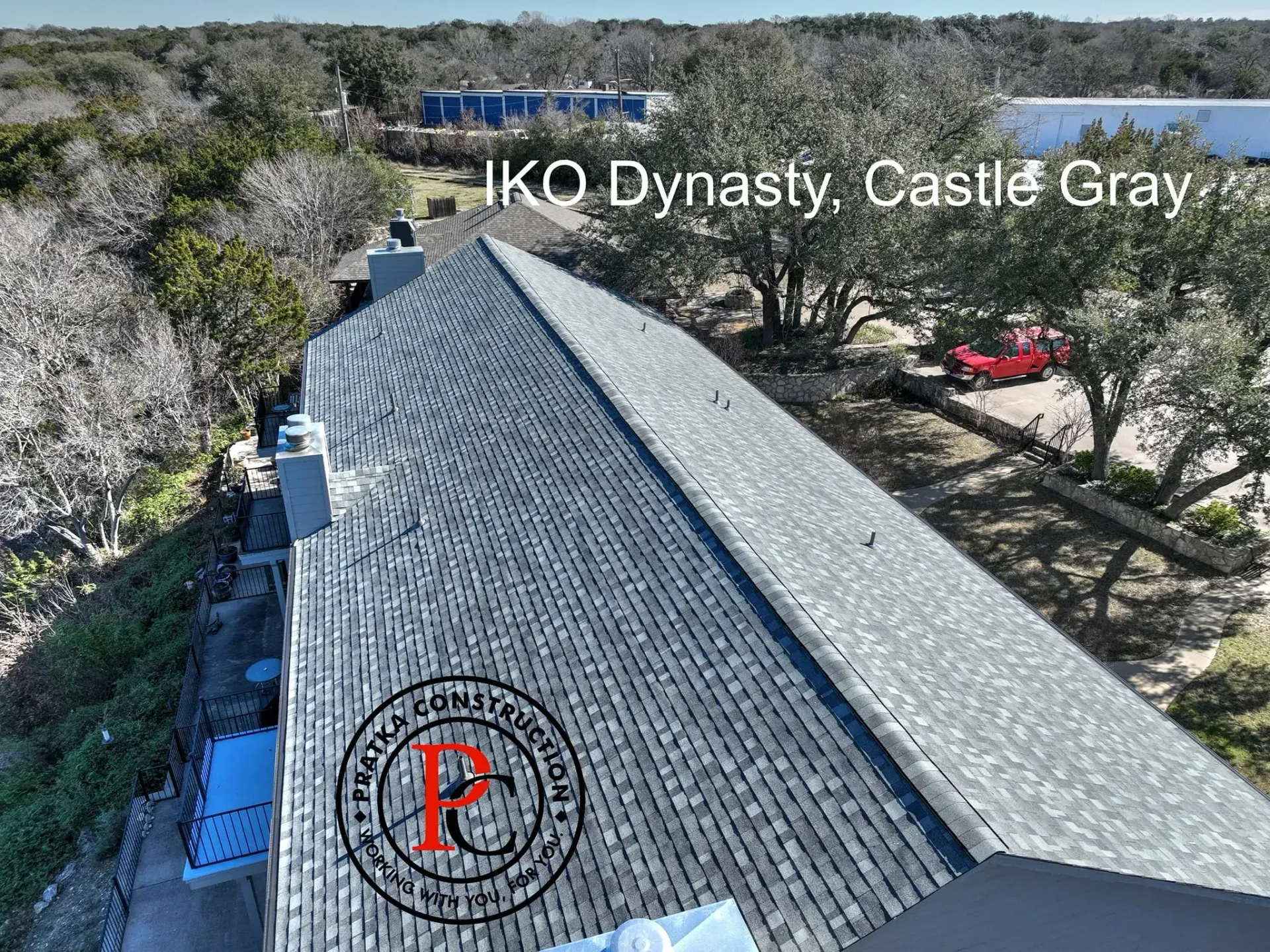 Aerial view of a roof covered in IKO Dynasty Castle Gray shingles. A red truck is parked in the distance.