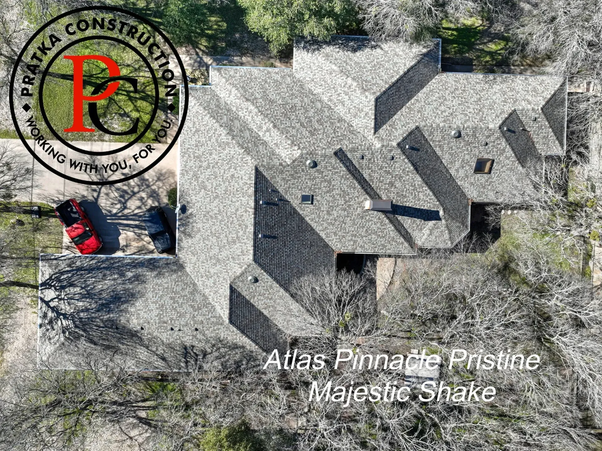 Overhead view of a house with a gray roof, red car in the driveway, and text for a construction company.