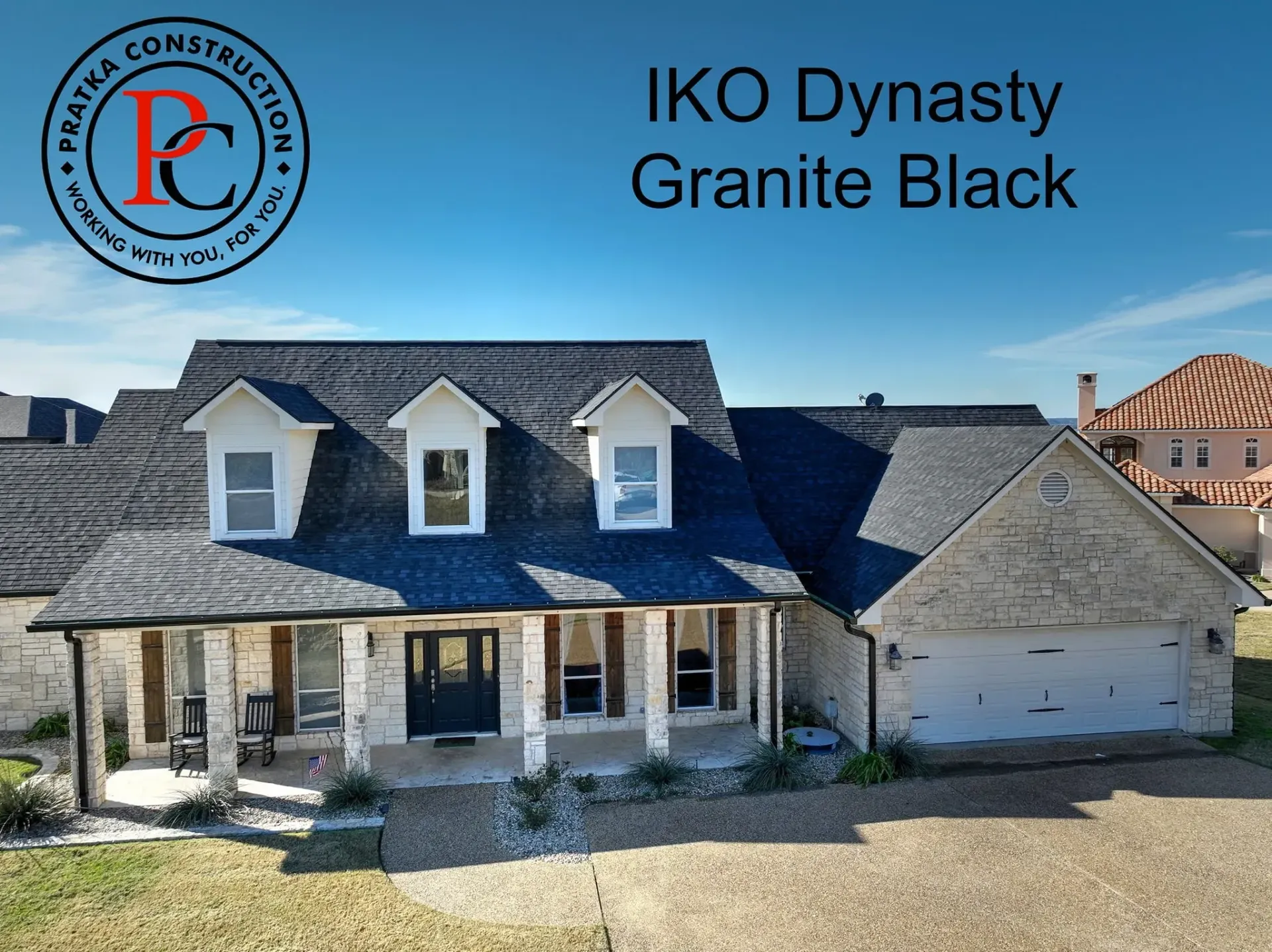 House with IKO Dynasty Granite Black roof, and logo of Praeka Construction on the top left.