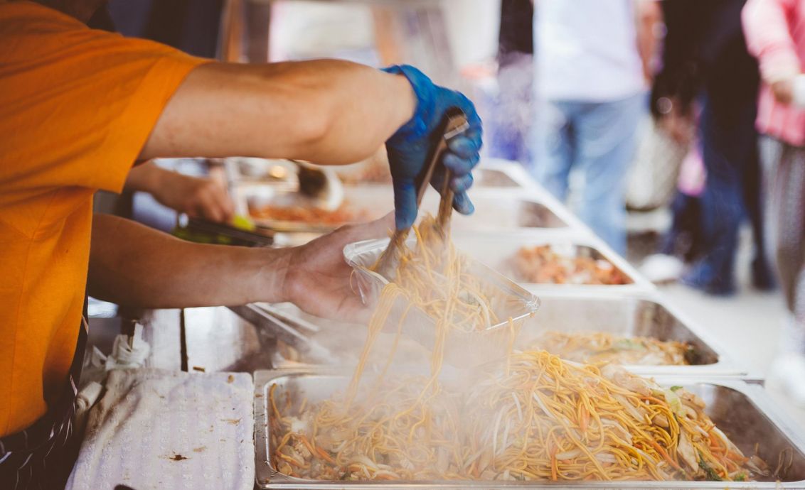 A person is cooking food on a grill at a food truck.