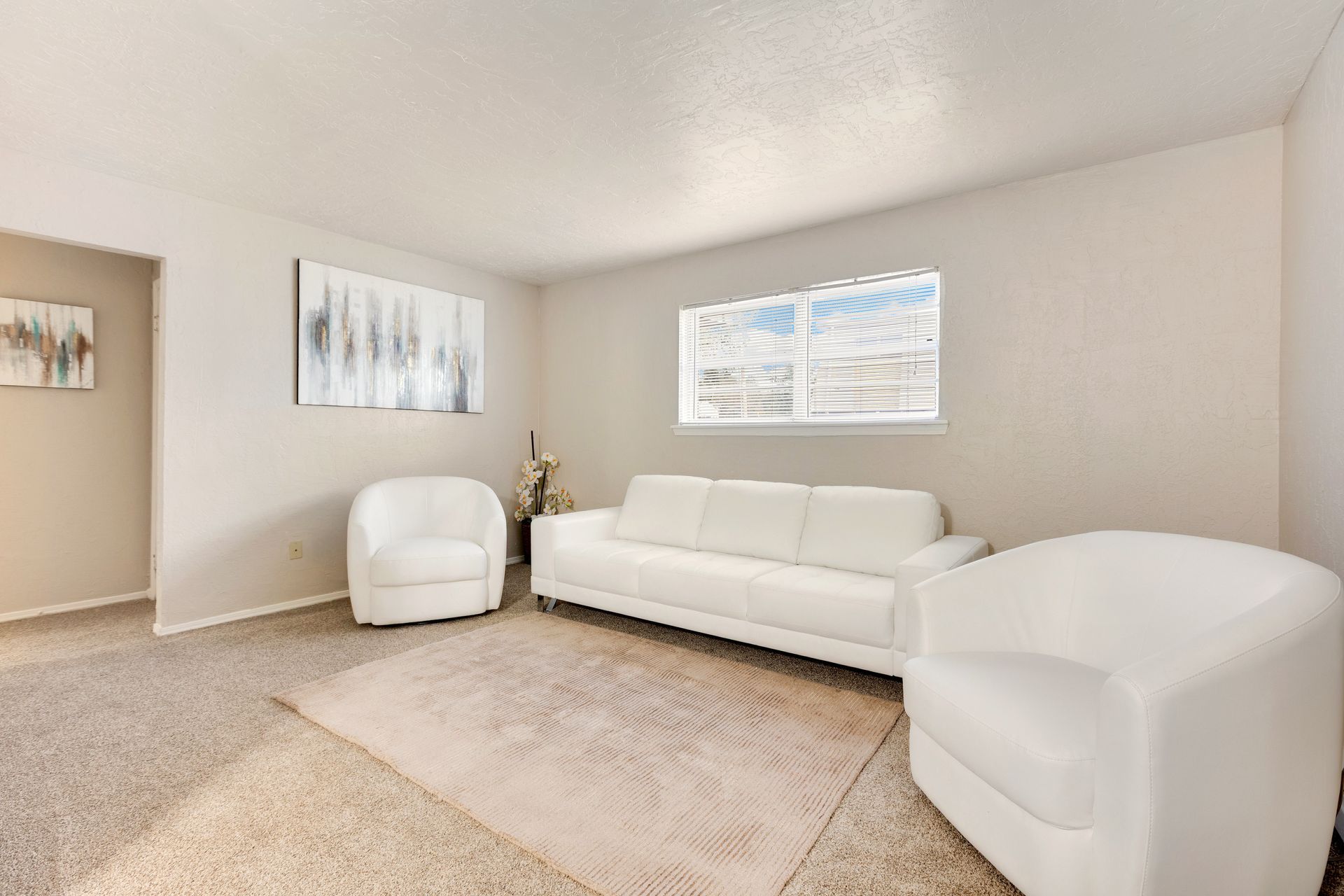 Living room with white furniture, neutral walls, carpet, and a window.