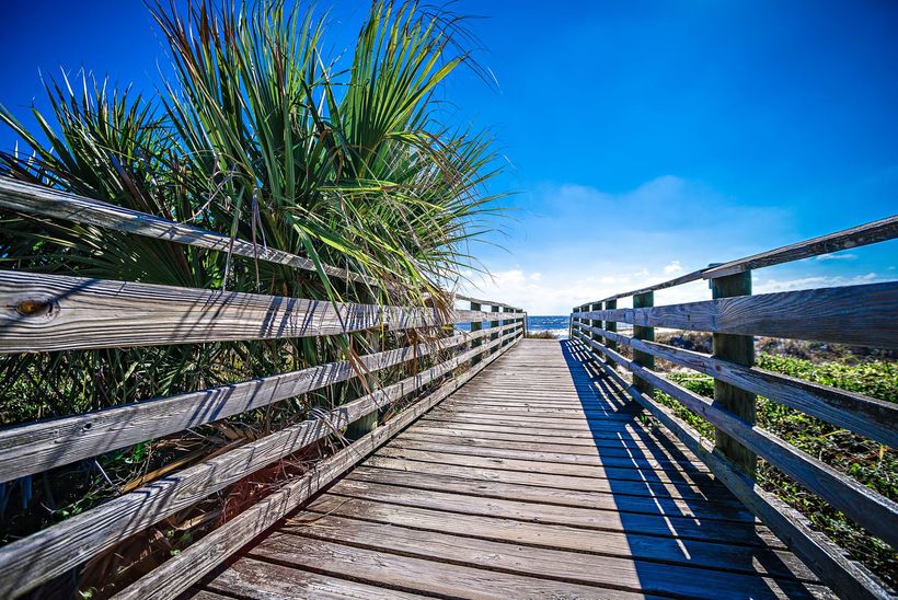 A wooden walkway leading to the beach with a wooden fence.