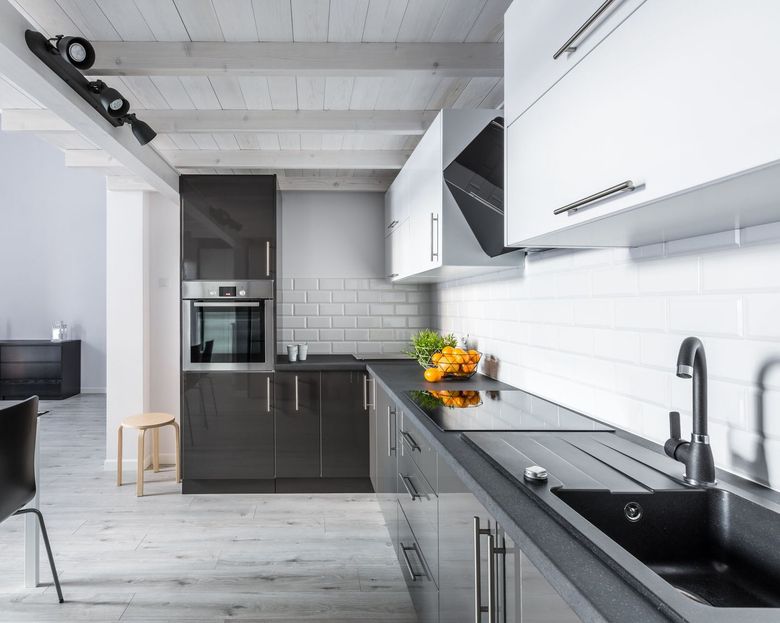 A kitchen with black and white cabinets , a sink , and a stove top oven.