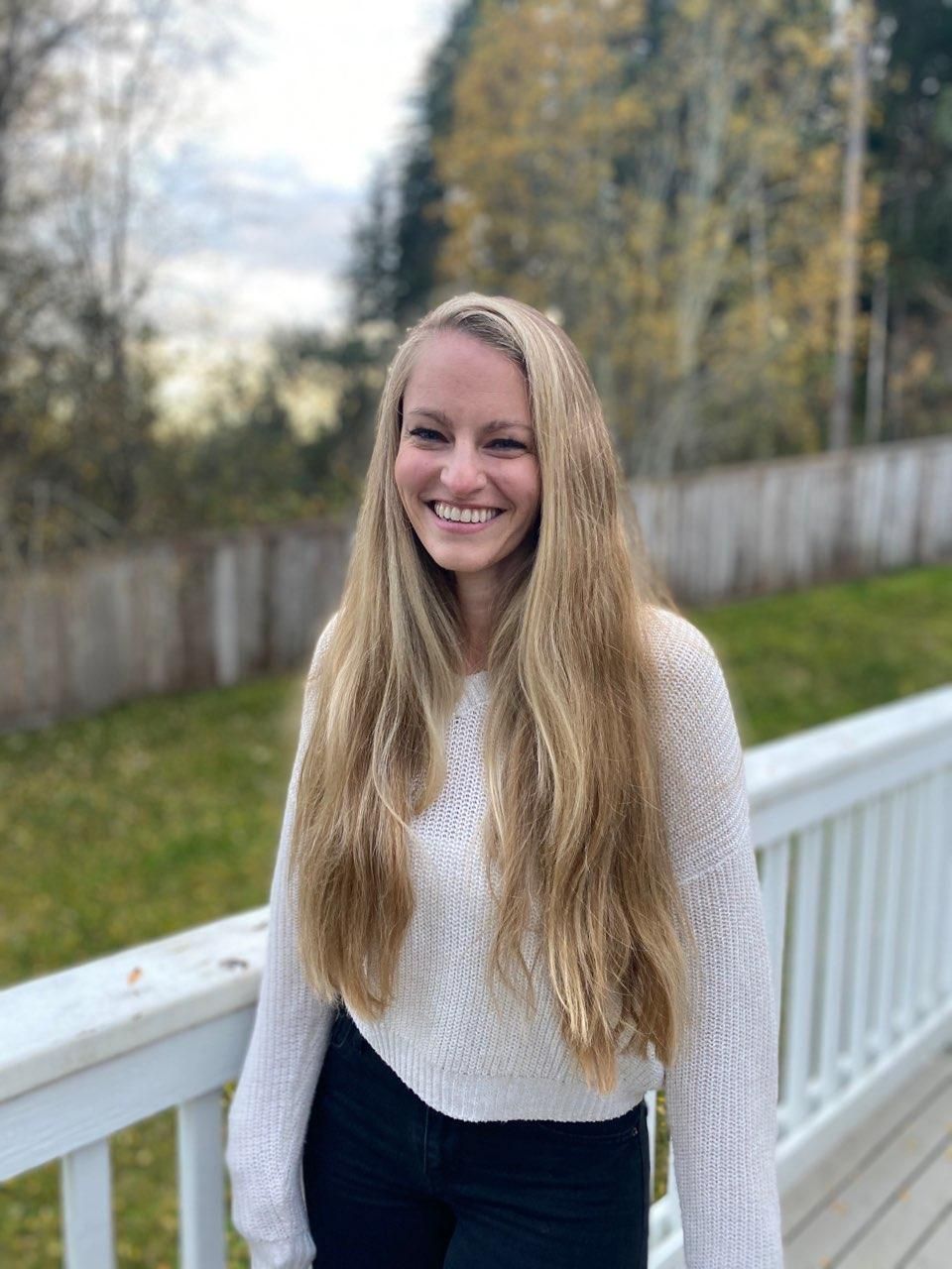 A woman with long blonde hair is standing on a deck.