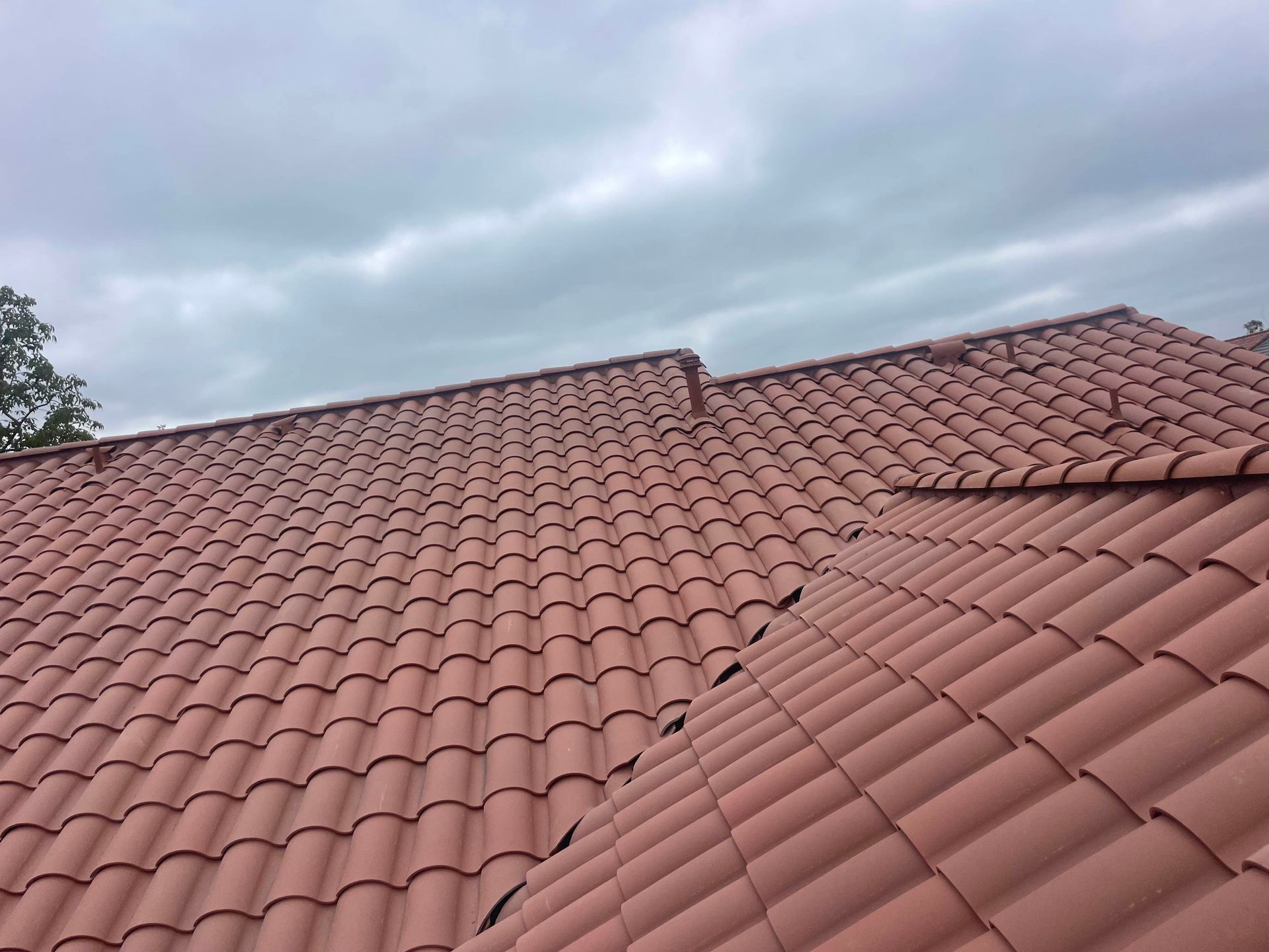 A red tiled roof with a cloudy sky in the background