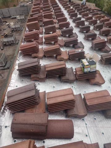 A lot of roof tiles are stacked on top of each other on a roof.