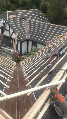 An aerial view of a house under construction with a roof being built.