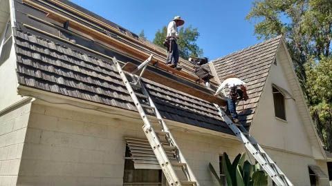 Two men are working on the roof of a house.