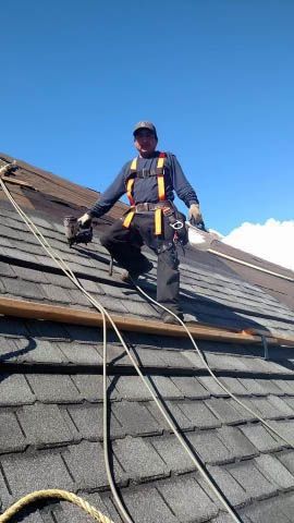 A man is standing on top of a roof with a ladder.