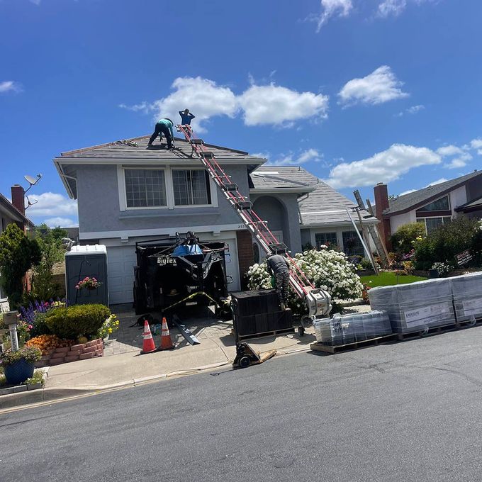 Two men are working on the roof of a house.