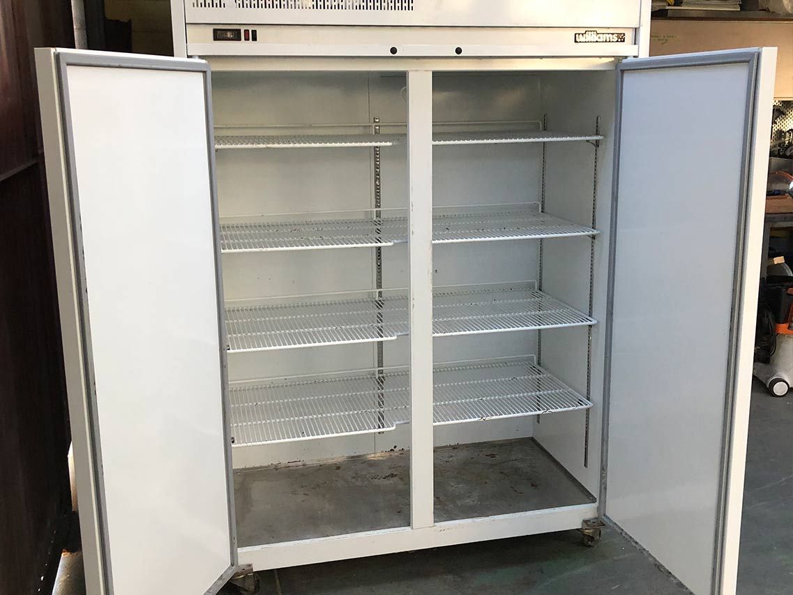 An empty refrigerator with the doors open and shelves.
