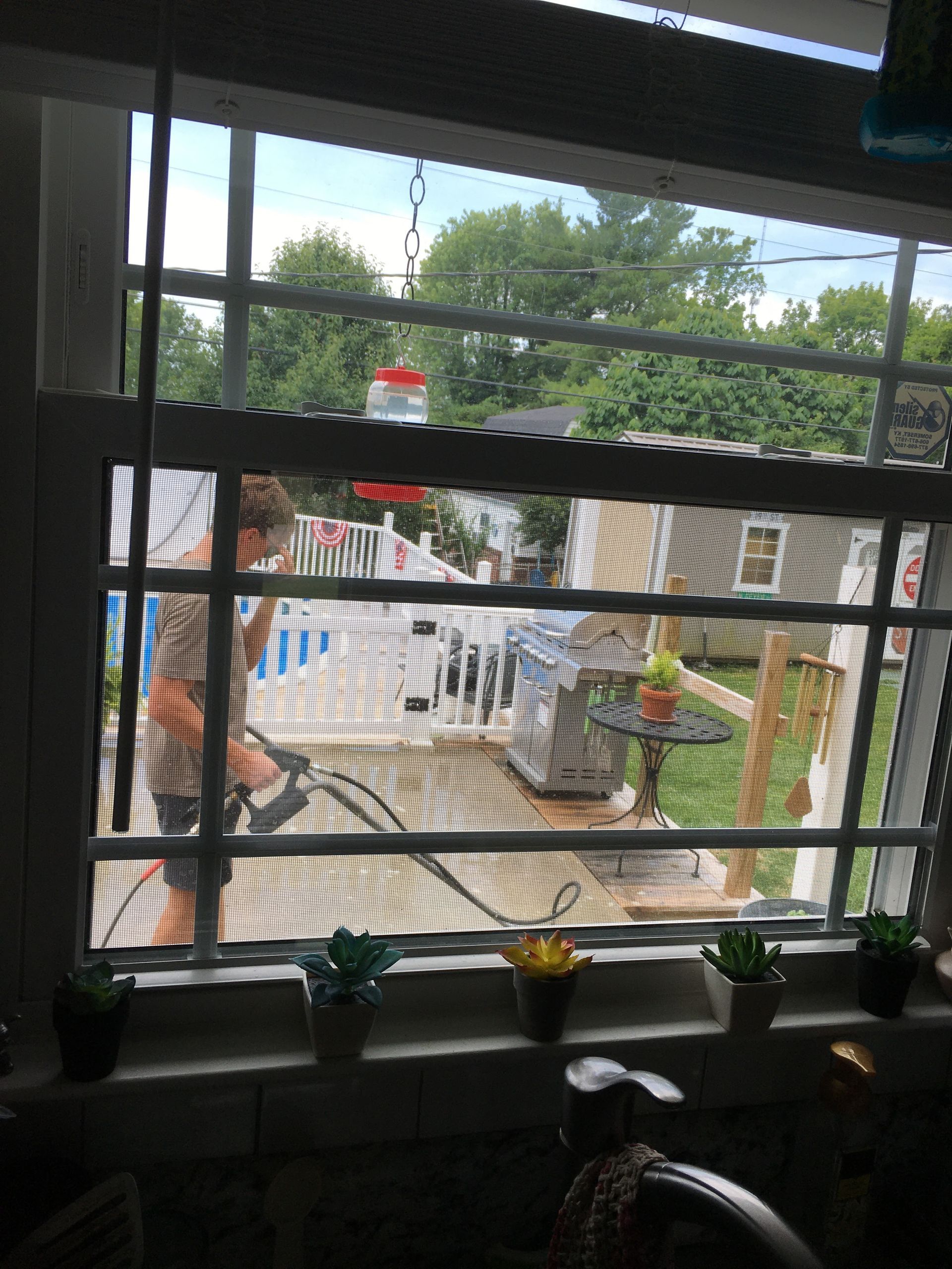 A person is standing in front of a window with a screen.