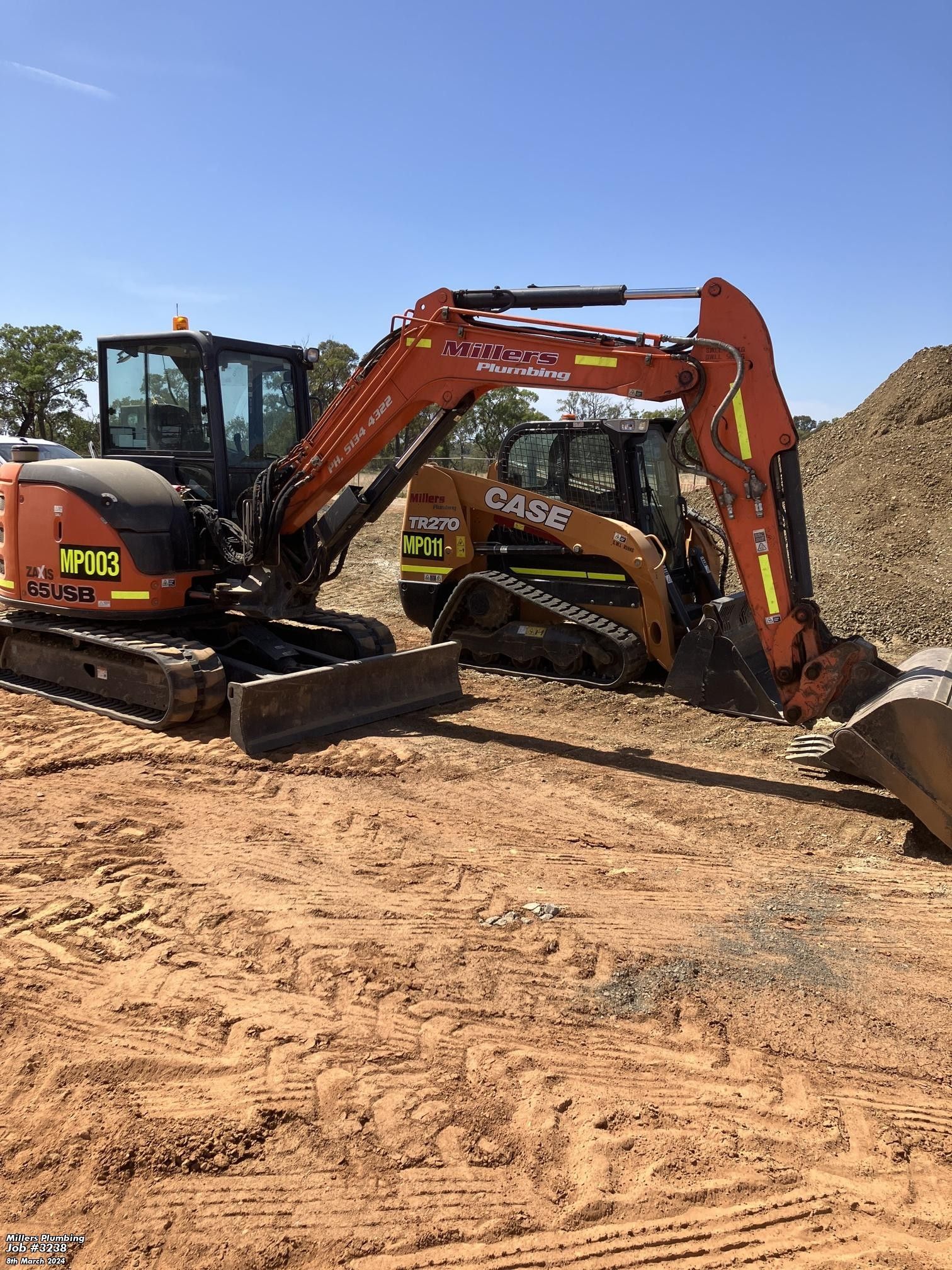 Two orange and yellow excavator next to each other.