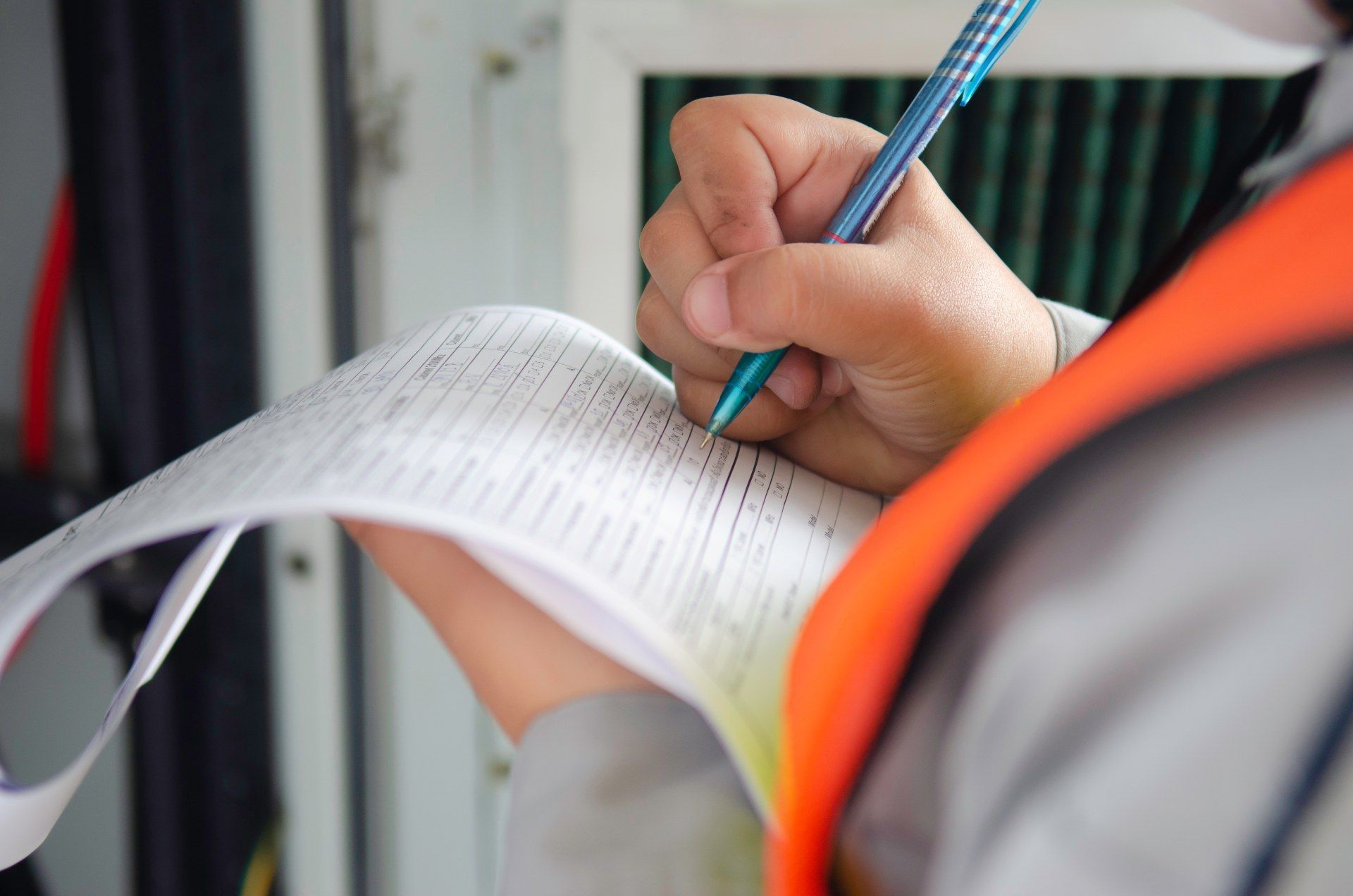 A person is writing on a piece of paper with a pen.