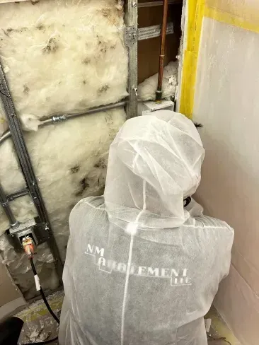 A person wearing a protective suit is working on a wall.