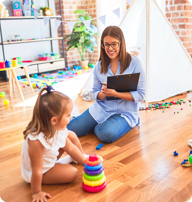 Woman and child playing with stacking rings in a brightly colored playroom.