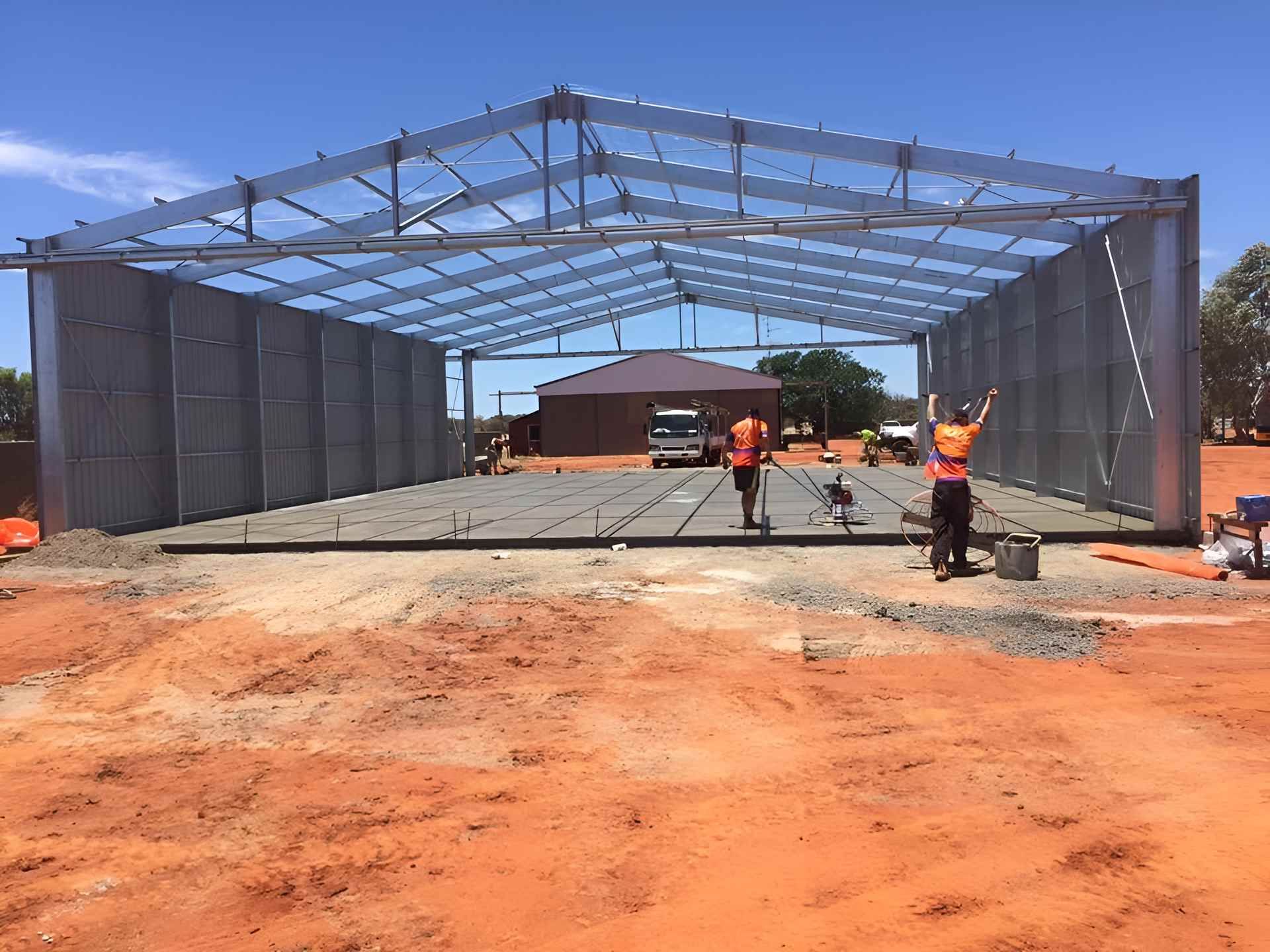 A Large Metal Structure Is Being Built In A Dirt Field — Heartland Concrete In Gillen, NT