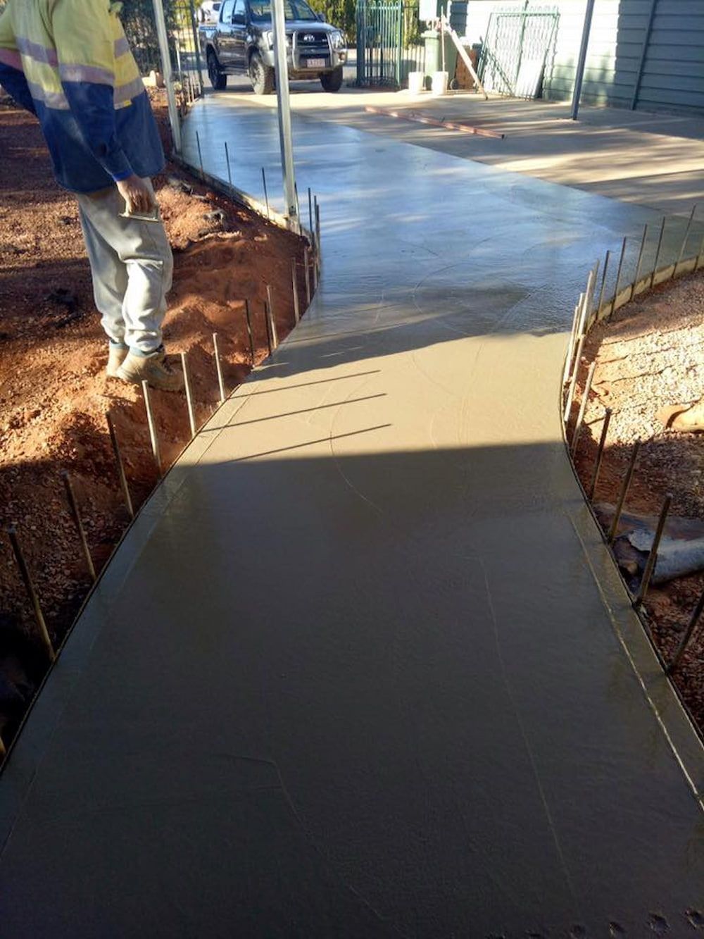 A Man Is Standing On A Concrete Walkway — Heartland Concrete In Gillen, NT