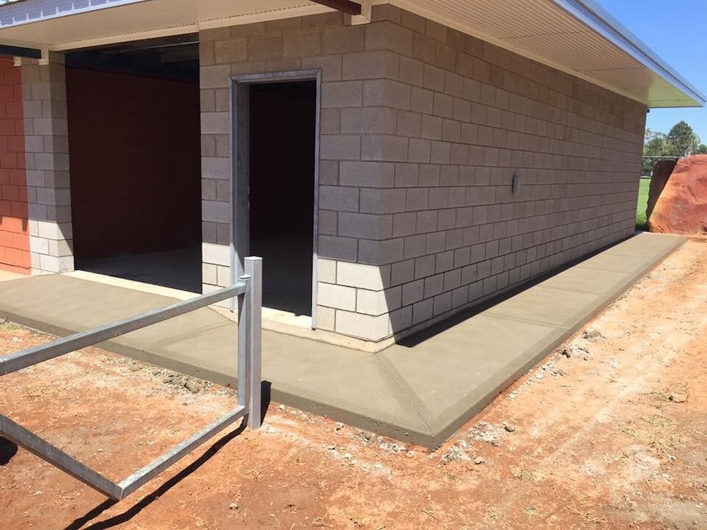 A Brick Building With A Concrete Walkway Leading To It — Heartland Concrete In Gillen, NT