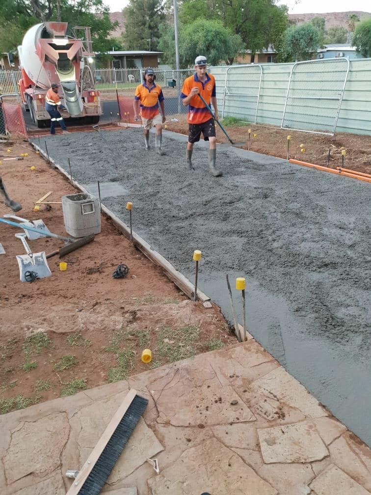 Two men are working on a concrete driveway with a mixer truck in the background — Heartland Concrete In Gillen, NT