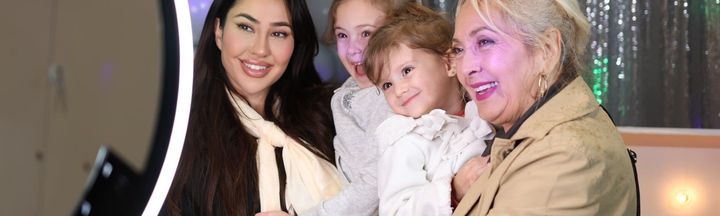 Four people smiling together while posed in front of a ring light.