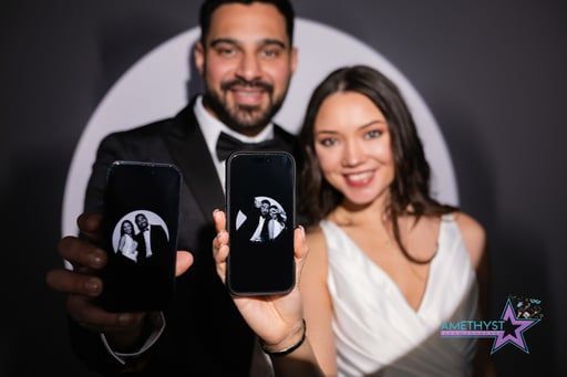 A man and woman smiling while holding up two smartphones displaying a matching circular photo of themselves.