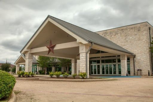Exterior view of a stone building with a large gabled entryway featuring a prominent star ornament and a gray metal roof.