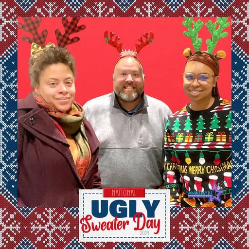 Three people wearing reindeer antler headbands pose for a photo framed with a 