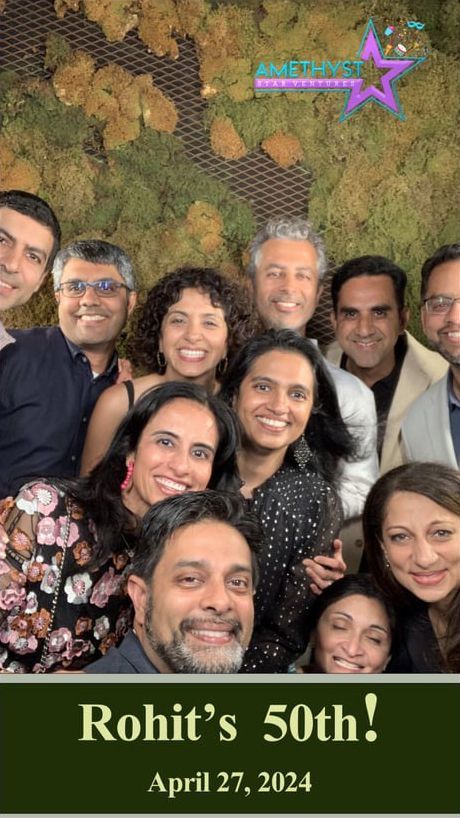 A group of friends smiling together in front of a mossy wall for 