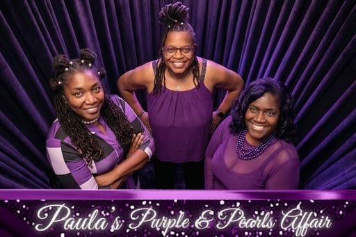 Three smiling people wearing purple pose in front of a purple curtain for